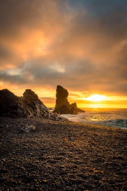 İzlanda, Djupalonssandur plajındaki volkanik lav oluşumlarının üzerinde gün batımı