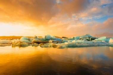 Yüzen buzdağları üzerinde çarpıcı bir günbatımı, Jokulsarlon Buzul Gölü, İzlanda