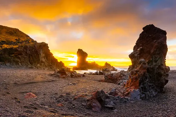 İzlanda, Djupalonssandur plajındaki volkanik lav oluşumlarının üzerinde gün batımı