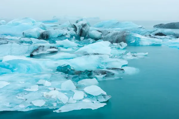 霧で激しい雨の下 アイスランドのジョガーロン氷河ラグーンの浮遊氷山 ストックフォト