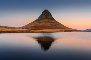 Kirkjufell 'in inanılmaz gündoğumu manzarası. Gölün üzerinde simetrik yansıma, İzlanda