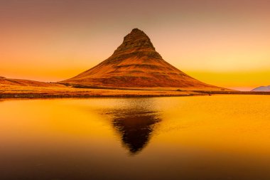 Kirkjufell 'in inanılmaz gündoğumu manzarası. Gölün üzerinde simetrik yansıma, İzlanda