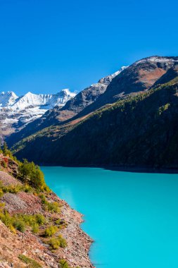 Autumnal landscape of the Lake Place Moulin, an artificial glacial lake with turquoise water in the italian Alps, on the border with Switzerland clipart