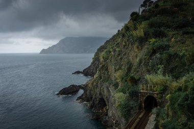 Deniz kenarındaki Cinque Terre, Liguria, İtalya tepelerindeki bir tünelden geçen demiryolu.