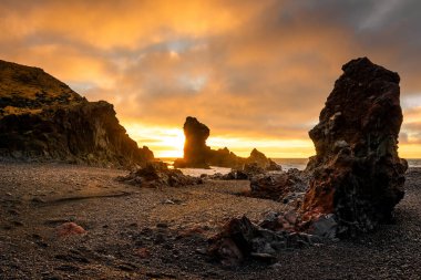 İzlanda, Djupalonssandur plajındaki volkanik lav oluşumlarının üzerinde gün batımı