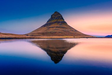 Kirkjufell 'in inanılmaz günbatımı manzarası. Gölün üzerinde simetrik yansıma, İzlanda