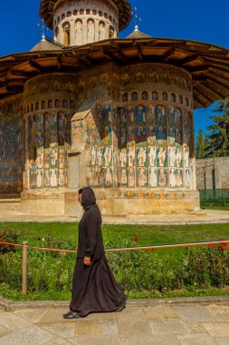 Voronet, Romanya, 29 Nisan 2024: Boyanmış manastırın önündeki Ortodoks rahibe