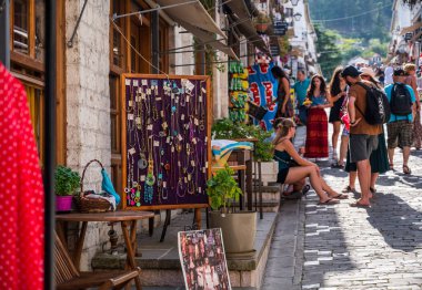 GJIROKASTER, ALBANIA - Eylül 2022: Arnavutluk 'un Cirokaster kentindeki çarşı ve dükkanlar, arka planda turistlerin bulunduğu eski kentin sokak manzarası.