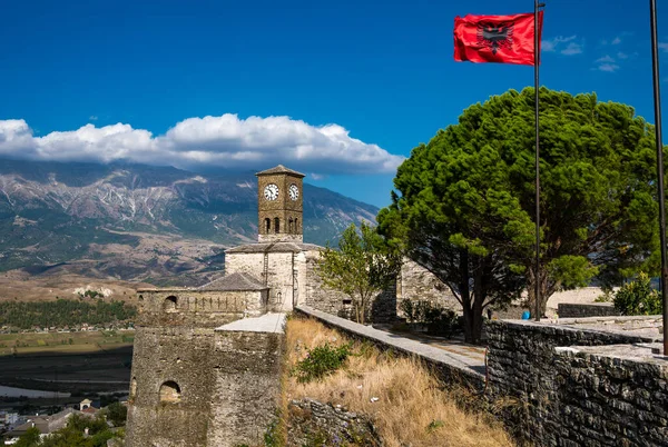 Clock Tower with waving Albanian flag in Gjirokaster Citadel or castle attraction in Albania, Europe