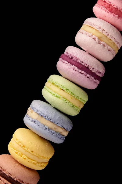 Colorful macarons cakes. Small French cakes. Sweet and colorful french macaroons. On black background