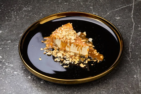 Cheesecake with caramel sauce on black background plate. Tasty caramel cheesecake.