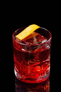 Klasik Negroni kokteyli. Siyah arka planda buz ve portakal kabuğuyla retro bardakta.