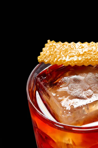 经典的尼可洛尼鸡尾酒 在黑色的背景上 用冰块和桔子皮装饰在复古玻璃杯中 免版税图库图片