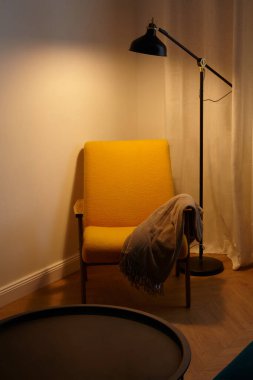 Modern bir lambayla güzelce tamamlanmış şık sarı bir sandalye, rahat bir köşe yaratmak için mükemmel.
