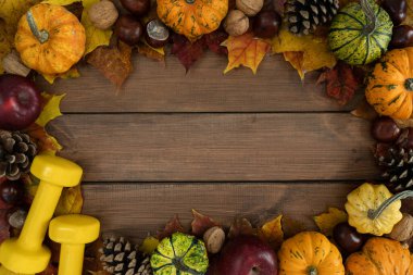 Şükran Günü ya da Cadılar Bayramı için sonbahar spor kompozisyonu. Dambıl, balkabağı, koni, fındık ve elma yapraklı sağlıklı bir spor çerçevesi. Ahşap üzerinde kopyalama alanı olan bir düz alan eğitimi..