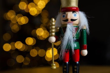 Noel fındıkkıranı ahşap figürü. Güzel, neşeli oyuncak asker dekorasyonu, arka planda Noel ağacı ışıkları var..