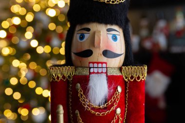 Noel fındıkkıranı ahşap figürü. Güzel, neşeli oyuncak asker dekorasyonu, arka planda Noel ağacı ışıkları var..