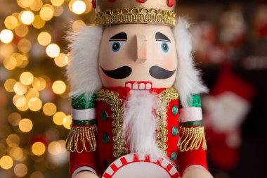 Noel fındıkkıranı ahşap figürü. Güzel, neşeli oyuncak asker dekorasyonu, arka planda Noel ağacı ışıkları var..