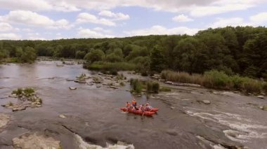 Akıntılı Manzaralı Nehirde Rafting Grubu. Parçalı bulutlu bir gökyüzü altında, yemyeşil ormanlar ve doğal güzelliklerle çevrili, yumuşak akıntılı bir nehirde rafting yapan insanların dinamik bir sahnesi..