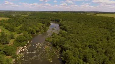 Akıntılı Manzaralı Nehirde Rafting Grubu. Parçalı bulutlu bir gökyüzü altında, yemyeşil ormanlar ve doğal güzelliklerle çevrili, yumuşak akıntılı bir nehirde rafting yapan insanların dinamik bir sahnesi..