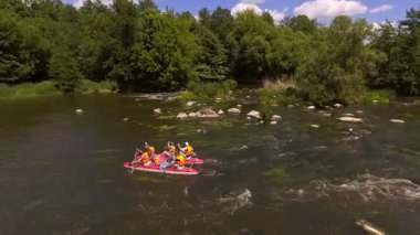 Akıntılı Manzaralı Nehirde Rafting Grubu. Parçalı bulutlu bir gökyüzü altında, yemyeşil ormanlar ve doğal güzelliklerle çevrili, yumuşak akıntılı bir nehirde rafting yapan insanların dinamik bir sahnesi..