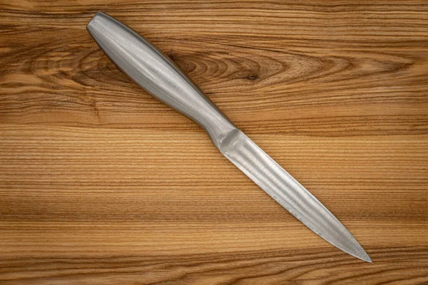 Big kitchen knife lying on a cutting board, gray kitchen knife. Steel kitchen chef\'s knife..