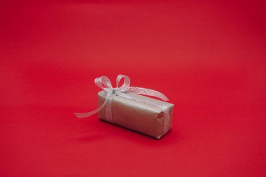 Gri kurdeleli küçük gri hediye kutusu. Noel hediyesi kutusu. Kırmızı arkaplanda izole edilmiş.