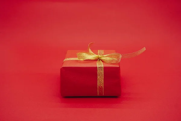Red gift box with gold ribbon. Christmas gift box. Isolated on a red background.