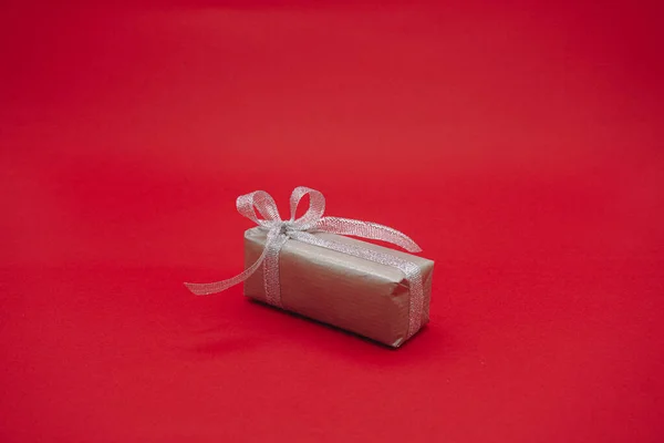 Małe Szare Pudełko Szarą Wstążką Świąteczne Pudełko Odizolowany Czerwonym Tle — Zdjęcie stockowe