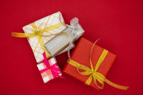 红色背景的四个圣诞礼品盒 圣诞节和新年的概念 顶部视图 — 图库照片