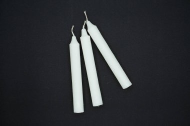 Siyah arka planda izole edilmiş bir sürü uzun beyaz mum, yakın plan, üst manzara. Beyaz uzun mumlar grubu.