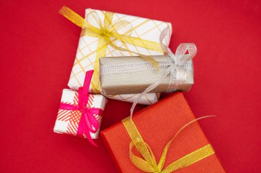 Mutlu yıllar ve mutlu noeller 2023 kırmızı hediye kutuları. Kırmızı arka planda dört Noel hediyesi kutusu.