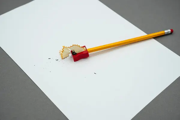 白いシートにシャープナー 黄色の木製の鉛筆と鉛筆削り — ストック写真