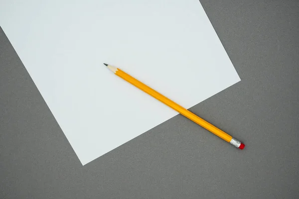 灰色の背景に空白の白い紙と黄色の鉛筆 テキストのコピースペース 上のビュー — ストック写真