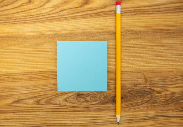 木製のテーブルの上に長い黄色の鉛筆と青の空白の付箋 トップ表示 — ストック写真