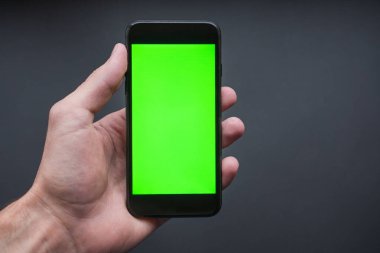 El ele tutuşan akıllı telefon, gri arka planda izole edilmiş, modern bir cep telefonu şekli. Yeşil ekran arkaplanı.