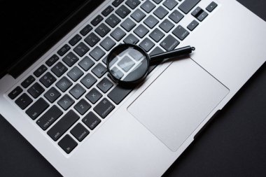 Bilgisayarda büyüteç, karanlık ofis masasında, arama konsepti..