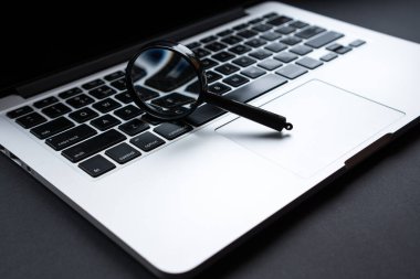 Ofis masası büyüteç, siyah saplı cam, dizüstü bilgisayara yaslanma, arama ve analiz konsepti.