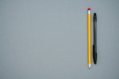 Uzun sarı bir kalem ve siyah bir kalem, gri arka planda, metin için boşluğu kopyala. Üst Manzara. Düz yatış stili. Okul malzemeleri..