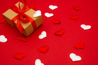 A small gift box on red background with hearts around. The concept of love.
