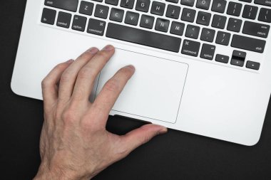 A man's hand rests on a laptop. The concept for working, touch, website, networking. Close up top view.