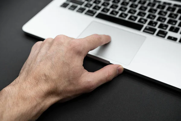 The finger touches the touchpad of the laptop. Technology concept. Isolated on black background.