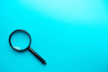 Magnifying glass on blue background. Top view. Flat lay. Copy space.