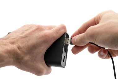 Man plugs the power bank battery with usb port. Charging mobile devices from power bank with usb cable. Isolated on white background.