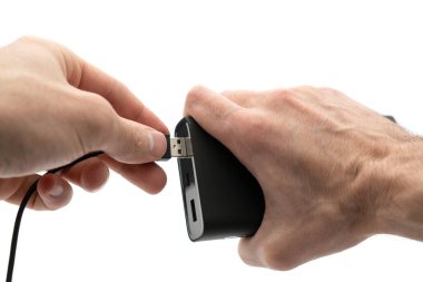 Black power bank with USB cable in hand on white background.
