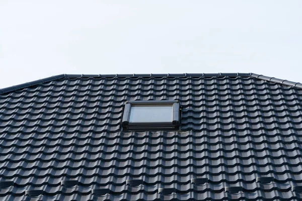 Tile installed on the roof. Metal tiles, roofing. A modern roof with a skylight.
