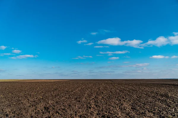 stock image View to spring landscape in sunny day with an agricultural plowed field and blue sky. Natural background.