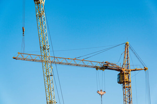 Two yellows hoisting cranes with blue sky background. Machines for construction. Construction concept.