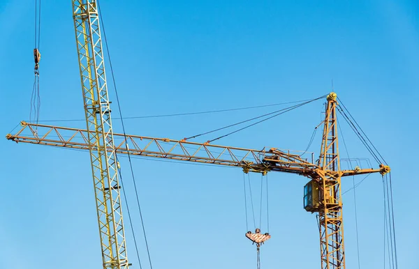 stock image Tall construction tower crane. Building crane on the background blue sky.
