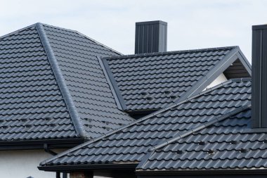 New black metal roof of a house with chimney. Roofing of metal profile. Metal roofing construction. clipart